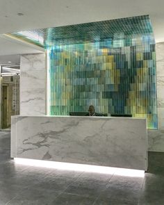 an office lobby with a marble counter and colorful tiles on the wall behind it,