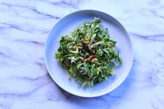 a white plate topped with lettuce and nuts on top of a marble counter