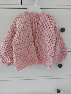 a pink and white sweater hanging from a hook