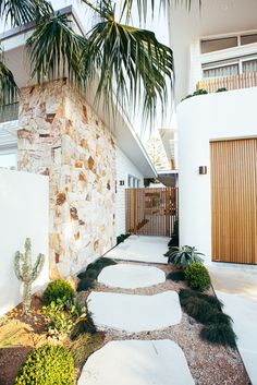 a white house with a palm tree in the front yard and walkway leading up to it