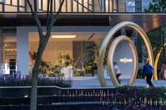 the entrance to an office building with people walking past it and trees in front of it