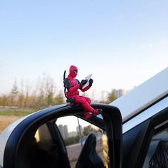 a toy is sitting on top of a car mirror