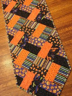 an orange and black tie is laying on the wooden floor next to a brown table