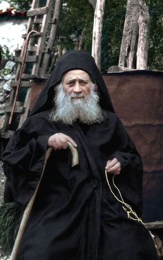 an old man with a long white beard wearing a black robe and holding a cane