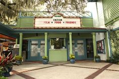 the exterior of a movie theater with plants and trees in pots on either side of the entrance