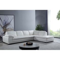 a white leather sectional sofa sitting in a living room next to a painting on the wall