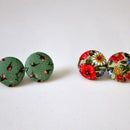 three different types of buttons on a white surface, one with red and green flowers