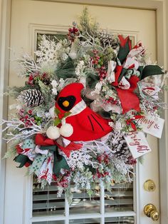 a christmas wreath on the front door decorated with red cardinal and pine cones, evergreens, snowflakes and berries