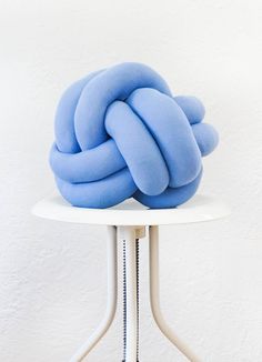 a blue knot sitting on top of a white table in front of a white wall