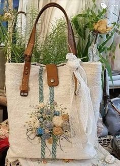 a white bag with flowers on it sitting on top of a table next to some plants