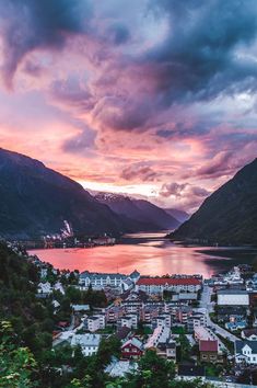 an aerial view of a town with mountains and water in the background at sunset or dawn