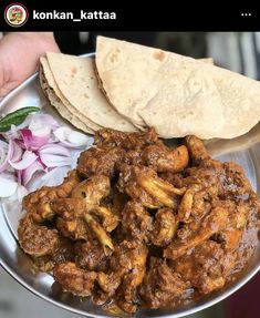 a person holding a metal bowl filled with meat and onions next to pita bread