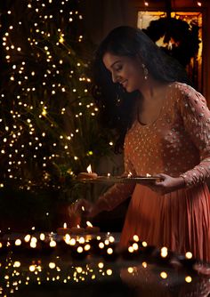 a woman in an orange dress is holding a plate and looking down at the table