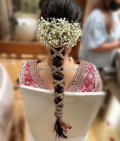 the back of a woman's head, with flowers in her hair and braid