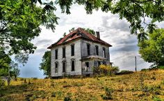 an old abandoned house sitting on top of a hill