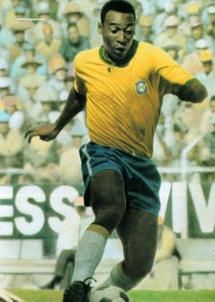 a man kicking a soccer ball on top of a field in front of a crowd