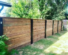 a wooden fence in the backyard with grass and trees around it, along side a house