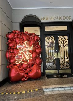 an entrance to a building decorated with red balloons that say all you need is love