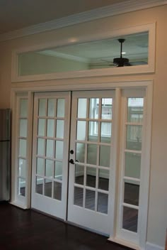 an empty living room with french doors leading into the kitchen