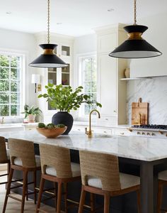 a kitchen with marble counter tops and black pendant lights