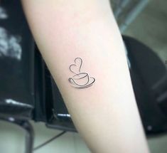 a small coffee cup tattoo on the left forearm and arm with a heart in it