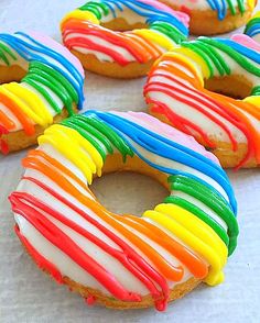 rainbow donuts with icing and sprinkles arranged on a table top