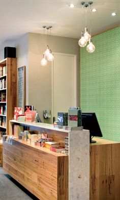 the front desk of a library with bookshelves in the background and lights hanging from the ceiling