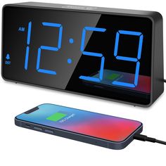 the alarm clock is connected to an iphone and charging it with a charger attached