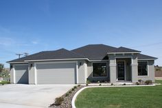 a gray house with two garages and green grass