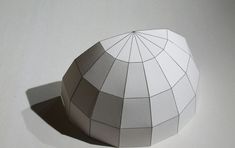 an origami ball on a white surface with a shadow from the top to the bottom