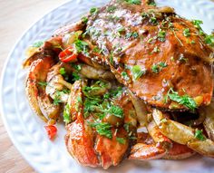 a white plate topped with crab and potatoes covered in gravy, garnished with parsley