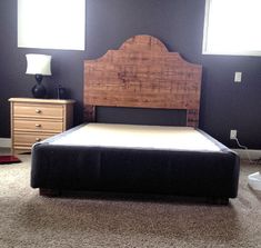 a bed with a wooden headboard and foot board sitting in a bedroom next to two windows