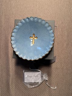 a blue plate with a gold cross on it and a clear plastic bag next to it