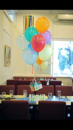 a bunch of balloons that are in the air over a table with place settings on it