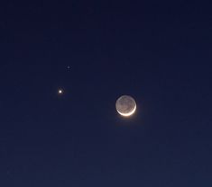 the moon and two stars are seen in the night sky