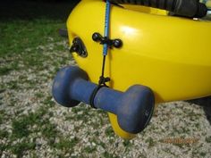 a yellow kayak sitting on top of a green grass covered field next to a blue hose