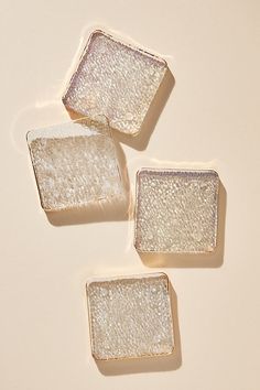 three square pieces of glass sitting on top of a white countertop next to each other