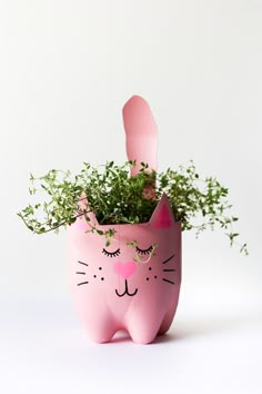 a pink cat planter with green plants in it