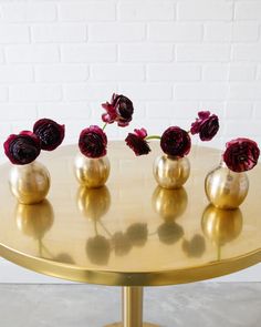 three gold vases with flowers in them on a table