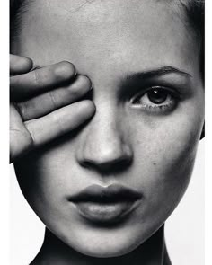 a black and white photo of a woman's face with her hand on her forehead