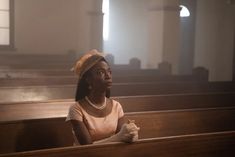 a woman sitting in the pews of a church with her hands on her knees