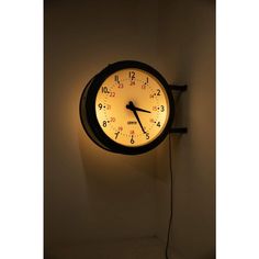 a clock that is on the wall with light coming from it's face and hands