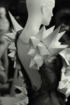 black and white photograph of a woman's back with origami pieces on it