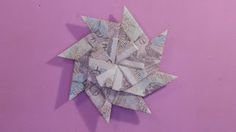 an origami star on a purple background with one dollar bill in the center