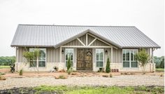 a small house with a metal roof and two large windows on the front door is shown