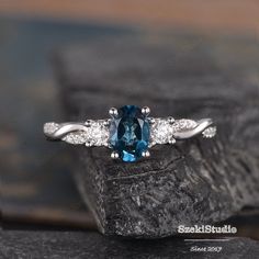 a blue and white diamond ring sitting on top of a rock