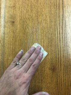 an older woman's hand holding a napkin on top of a wooden table