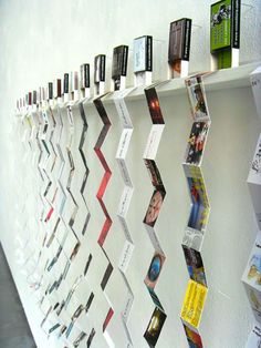 a wall with many different items on it and hanging from the side, along with several cards attached to each shelf