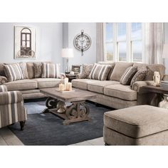 a living room filled with furniture and a clock mounted to the wall above it's windows