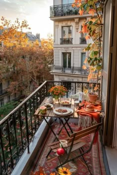 an outdoor table and chairs on a balcony with autumn foliage in the foreground at sunset